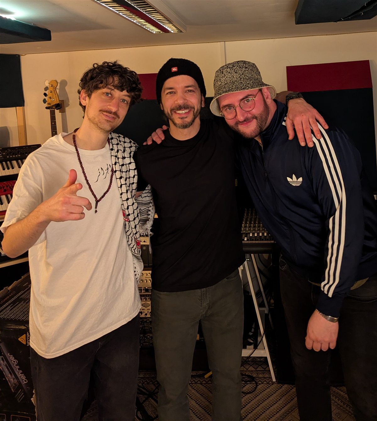 Three people posing together in a recording studio